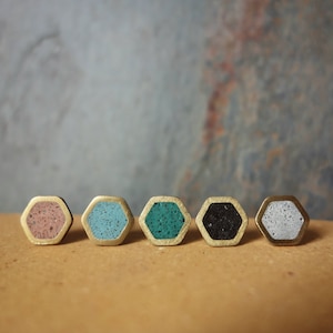 Peut inclure: Cinq boucles d'oreilles hexagonales avec des bords dorés et des intérieurs mouchetés de différentes couleurs : rose, turquoise, vert, noir et blanc.