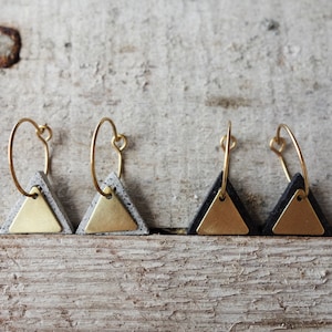 Puede incluir: Un par de pendientes de aro dorados con colgantes triangulares de hormigón. Los colgantes de hormigón están salpicados de blanco y negro.