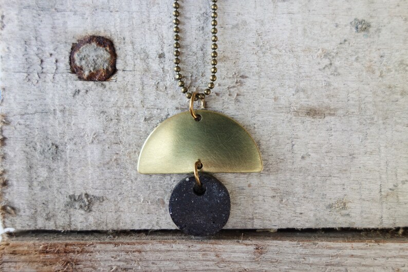 May include: A gold necklace with a half-circle pendant and a black round pendant.
