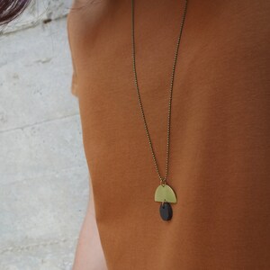 May include: A gold necklace with a black and gold pendant. The pendant is a half circle shape with a smaller circle hanging from it.