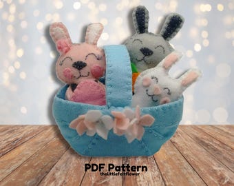 May include: A blue felt basket with three felt bunny rabbits inside. The bunnies are pink, gray, and white. The basket has a white felt flower embellishment.  PDF Pattern thelittlefeltflower