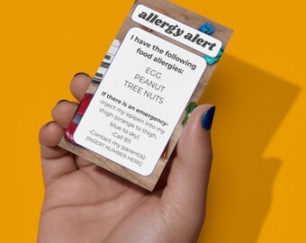 May include: A rectangular allergy alert card with the words "allergy alert" at the top. The card lists food allergies: egg, peanut, and tree nuts. Instructions for emergency treatment and contact information are also included.