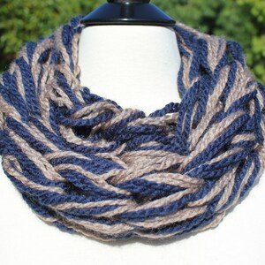 May include: A blue and brown knitted infinity scarf. The scarf is made of a soft, chunky yarn and is perfect for keeping warm in the winter.
