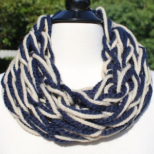 May include: A thick, chunky knit infinity scarf in navy blue and cream white. The scarf is made of soft yarn and is perfect for keeping warm in the winter.