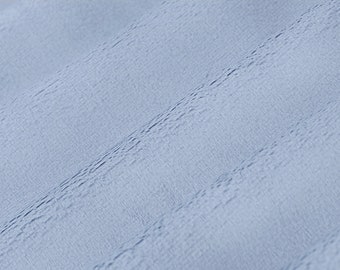 May include: A close-up of a light blue fabric with a textured surface.