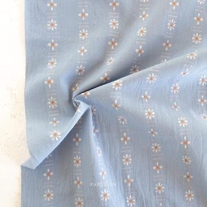 May include: Light blue cotton fabric with a white and orange floral pattern. The fabric has a slightly textured surface.