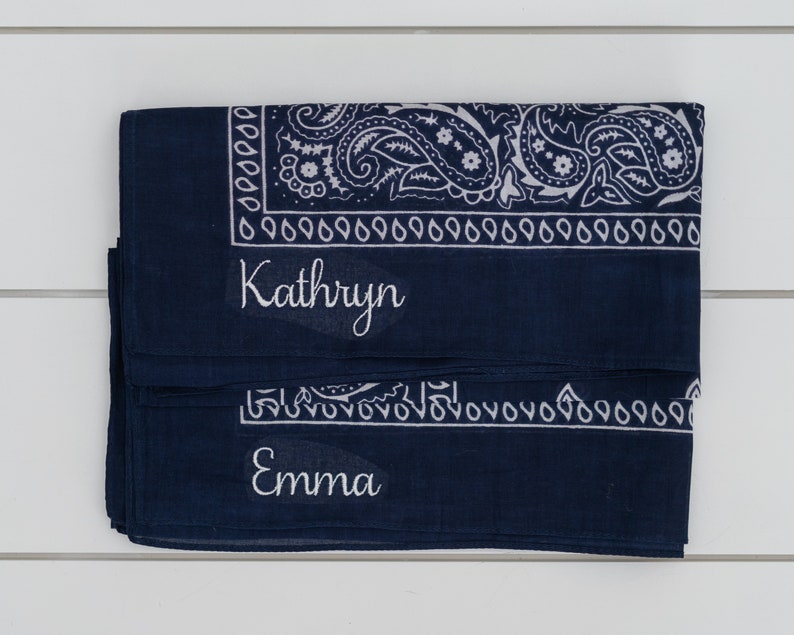 May include: A dark blue bandana with a white paisley pattern and the names "Kathryn" and "Emma" embroidered on it.