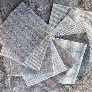 May include: A collection of eight fabric swatches in various shades of gray with different patterns, including houndstooth, herringbone, and solid.