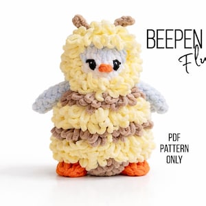 May include: A handmade, fluffy crochet owl in shades of yellow, brown, blue, and orange. The owl has a textured, layered design, with the text "BEEPEN Fluffy" and "PDF PATTERN ONLY" in black.
