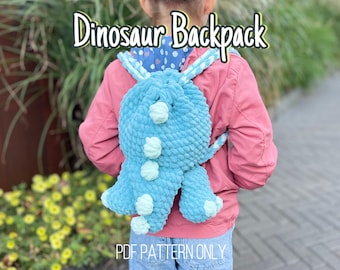 May include: A blue crocheted dinosaur backpack with white pom-poms. The backpack is being worn by a child. The text "Dinosaur Backpack" is written in yellow letters above the backpack. The text "PDF PATTERN ONLY" is written in white letters below the backpack.
