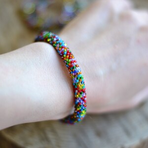 May include: A colourful beaded bracelet with a rainbow of colours, including red, orange, yellow, green, blue, and purple.