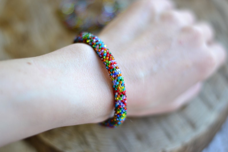 May include: A colourful beaded bracelet with a rainbow of colours, including red, orange, yellow, green, blue, and purple.