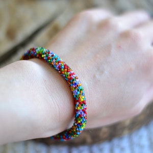 May include: A colourful beaded bracelet with a variety of colours, including red, blue, green, and yellow.