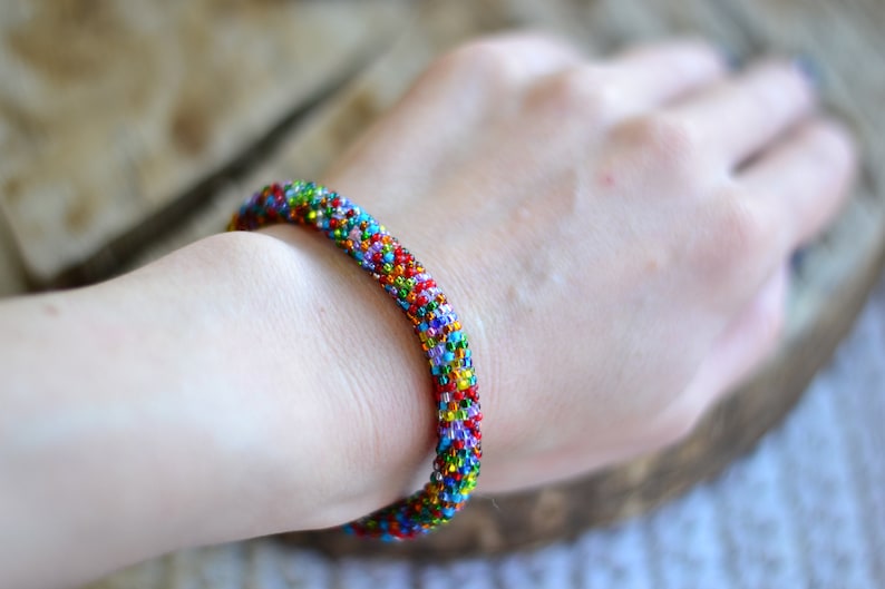 May include: A colourful beaded bracelet with a variety of colours, including red, blue, green, and yellow.
