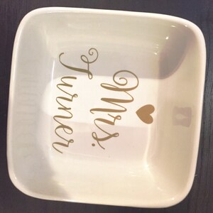 Puede incluir: Un joyero de cer&aacute;mica blanco con un coraz&oacute;n dorado y el texto "Mrs. Turner" en letras doradas.