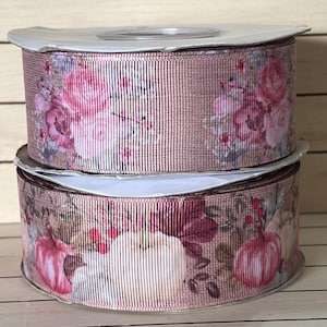 May include: Two stacked spools of grosgrain ribbon. The top spool features a pattern of pink roses and small floral accents on a tan background. The bottom spool displays a print of white and pink pumpkins with red berries and brown leaves.