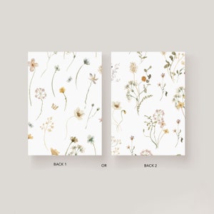 May include: Two different designs for a floral patterned card. The first design features a light pink flower, yellow flowers, and green leaves. The second design features a white flower, yellow flowers, and green leaves. Both designs have a white background.