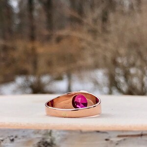 Puede incluir: Un anillo de oro rosa con una sola piedra preciosa redonda de color rosa.
