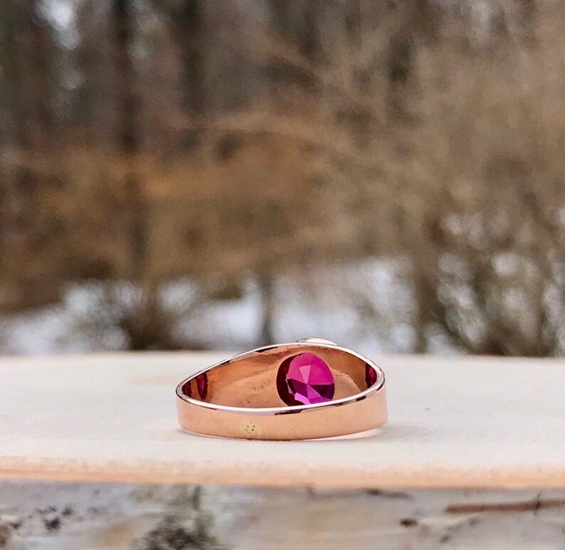 Puede incluir: Un anillo de oro rosa con una sola piedra preciosa redonda de color rosa.