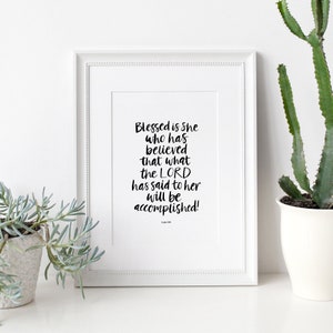 May include: A white framed print with a black and white inspirational quote: "Blessed is She who has believed that what the LORD has said to her will be accomplished!"