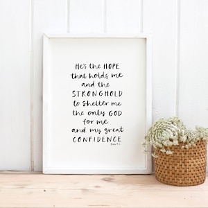 May include: White framed print with a black and white inspirational quote: "He's the HOPE that holds me and the STRONGHOLD to shelter me the only GOD for me and my great CONFIDENCE".
