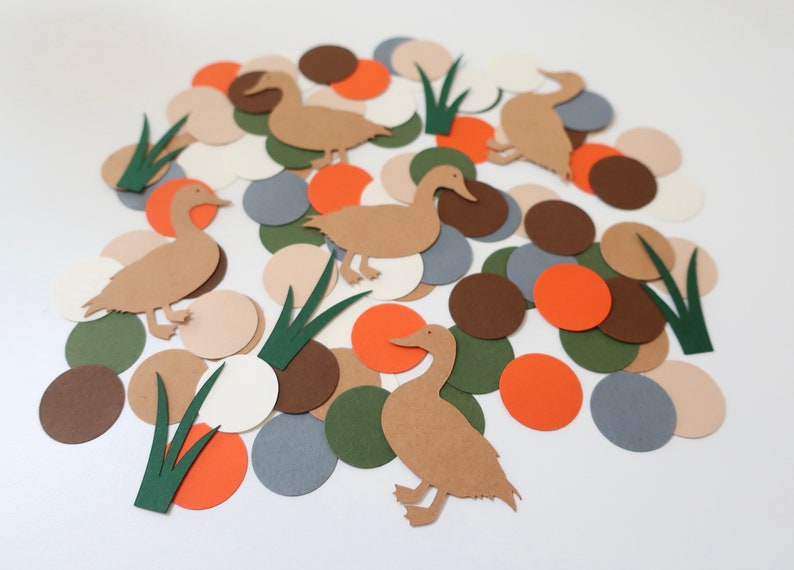 May include: A collection of paper cutouts featuring brown ducks, green grass, and colorful circles in shades of brown, orange, white, and gray.