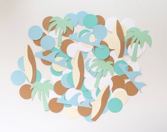 May include: A collection of paper cutouts in brown, blue, and green, featuring palm trees, surfboards, and waves. The cutouts are scattered on a white background.