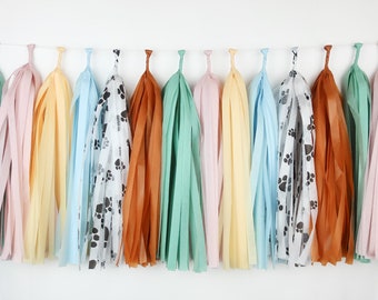 May include: A garland of tissue paper tassels in various colors, including light blue, yellow, orange, green, and pink. Some tassels have a white background with black paw prints.
