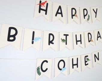 Puede incluir: Bandera blanca con letras negras que deletrean "Happy Birthday Cohen" con siluetas de dinosaurios en cada bandera.