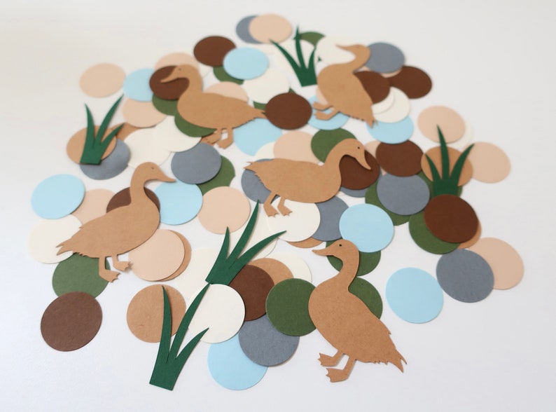 May include: Brown paper duck cutouts with green grass and brown, beige, gray, and blue paper circles.