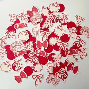 Pu&ograve; includere: Una collezione di ritagli di carta a tema italiano rossi e bianchi. I ritagli includono fette di pizza, pomodori, limoni, pasta, caffettiere e altre icone del cibo italiano. I ritagli sono sparsi su una superficie bianca.
