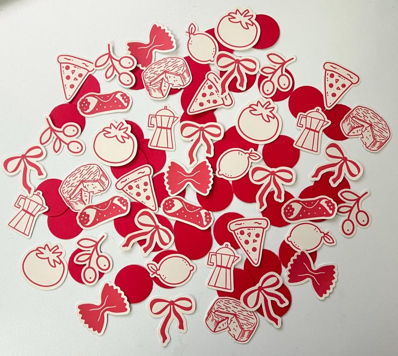 Pu&ograve; includere: Una collezione di ritagli di carta a tema italiano rossi e bianchi. I ritagli includono fette di pizza, pomodori, limoni, pasta, caffettiere e altre icone del cibo italiano. I ritagli sono sparsi su una superficie bianca.