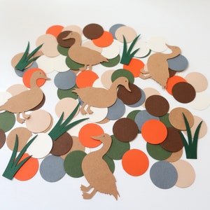 May include: A collection of brown paper duck cutouts on a white background surrounded by various colored paper circles. The circles are in shades of brown, orange, green, gray, and beige.
