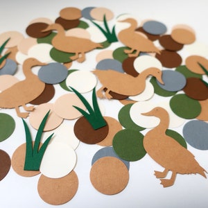 May include: A collection of brown, green, beige, and gray paper circles and duck cutouts. The duck cutouts are brown and have a simple design. The circles are scattered on a white background.