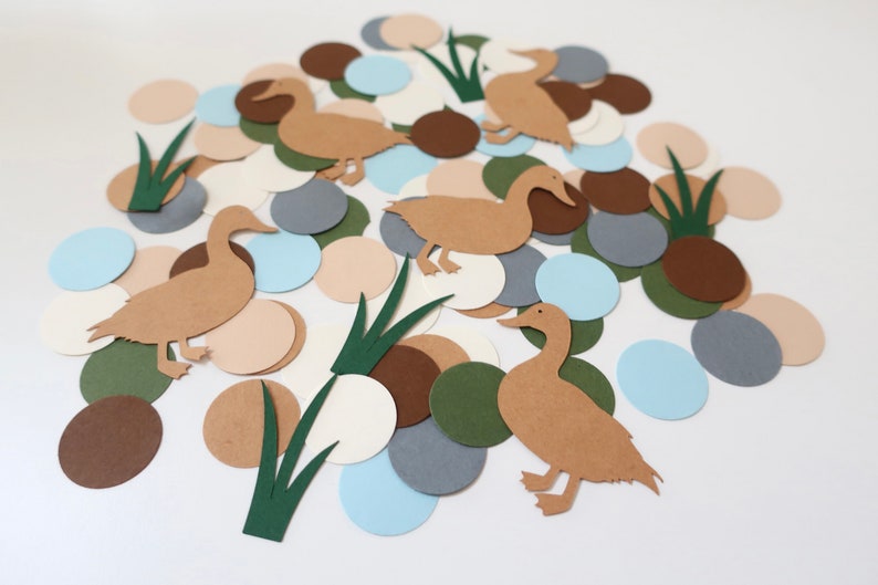 May include: A collection of brown paper duck cutouts, green paper grass cutouts, and assorted colored paper circles in shades of brown, beige, blue, and gray.