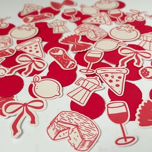 Pu&ograve; includere: Una collezione di ritagli di carta rossi e bianchi a tema italiano. I ritagli includono fette di pizza, calici, pomodori, farfalle, limoni, ciliegie, caffettiere e formaggio. I ritagli sono sparsi su una superficie bianca.