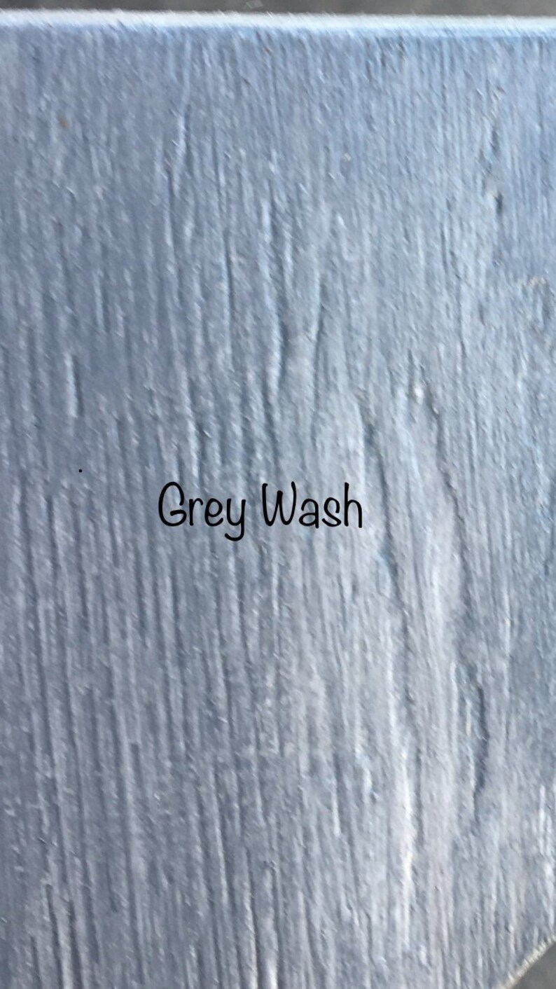 May include: A close-up of a textured, gray painted surface with the words "Grey Wash" written in black.