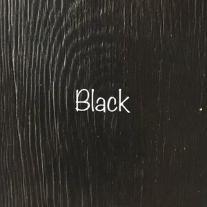 May include: Close-up of a black wood grain surface. The word "Black" is written in white text on the surface.