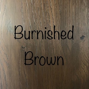 May include: A close-up of a wood grain surface with the text "Burnished Brown" written in black.