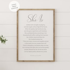 May include: A framed print with a white background and gray text. The text reads "She Is" and includes a quote about a woman's strength and dignity. The quote is from Proverbs 31:25.