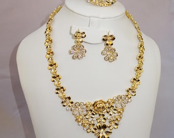 May include: A gold-tone jewelry set with a necklace, bracelet, and earrings. The set features a floral design with clear rhinestones.