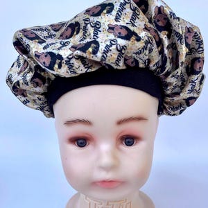 May include: A satin sleep cap with a black elastic band. The cap is printed with a gold and black pattern that says "Black Princess" repeatedly.