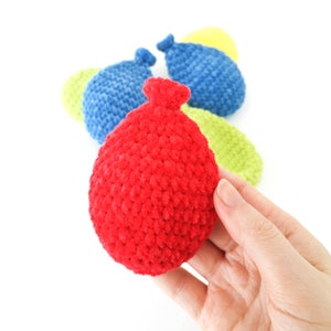 May include: A set of five crocheted plush balls in red, blue, and green. The balls are shaped like water balloons and are made with a soft, fuzzy yarn.