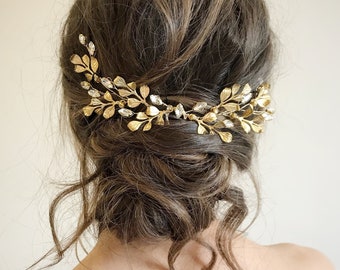 May include: A gold leaf and crystal hair comb with a delicate design. The comb is worn in a woman's hair, creating a romantic and elegant look.