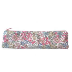 Può includere: Astuccio rettangolare con cerniera rosa, ornato da un motivo floreale. Il tessuto presenta fiori rosa, blu e verdi su sfondo bianco. Design semplice ed elegante.