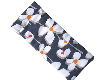 May include: A gray fabric eye mask with a white floral pattern. The flowers have orange centers.