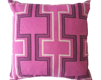 May include: Pink throw pillow with a geometric pattern of white and dark purple squares and rectangles.