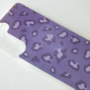 May include: A clear phone case with a purple leopard print design.