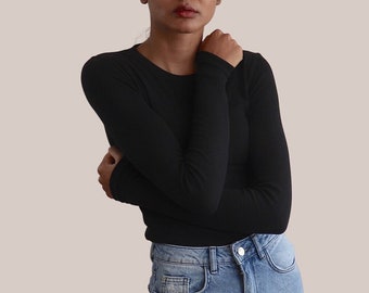 May include: A person wearing a black long-sleeved shirt and light blue jeans with distressed details.