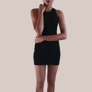 May include: A woman wearing a black sleeveless dress and black ankle boots.